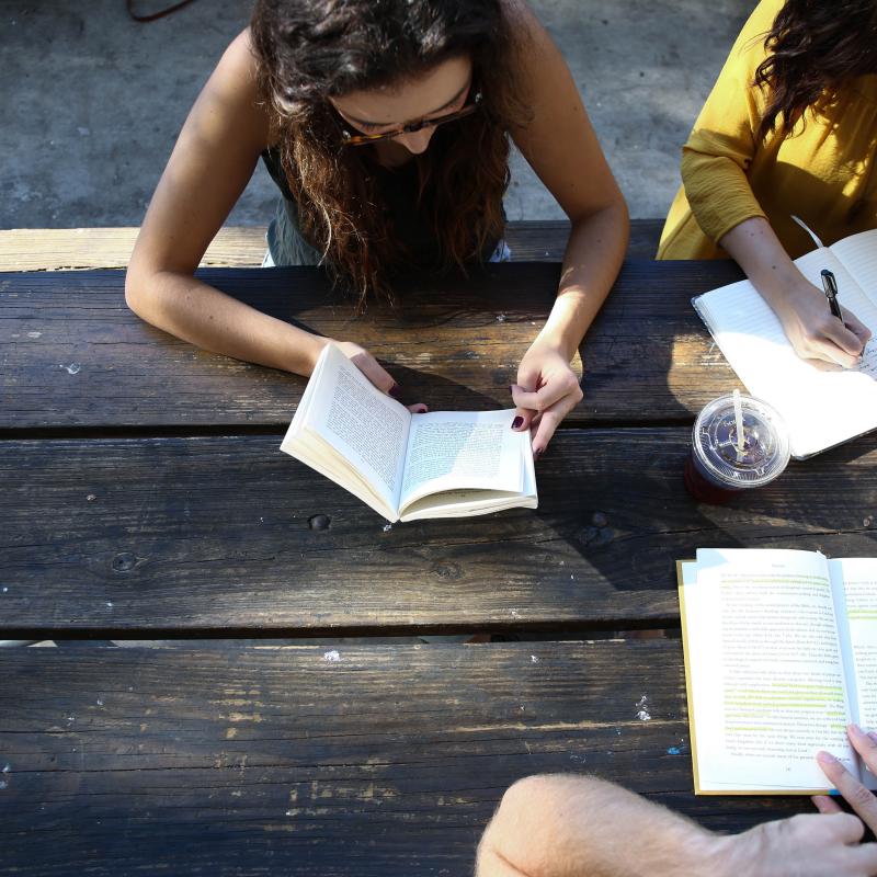 Student reading outside Three students sitting at table reading